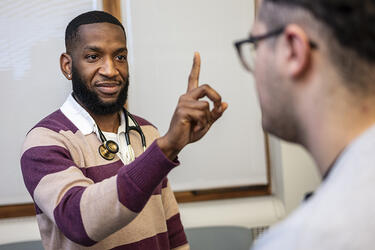 a clinician stands facing a patient with one finger raised while conducting a extraocular muscle function testing